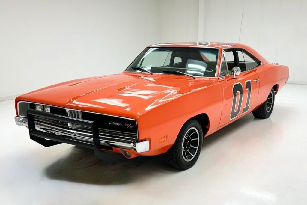 1969 Dodge Charger R/T in orange, side profile with hidden headlights and Coke-bottle styling.